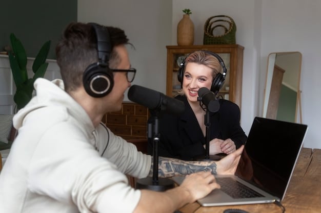 Two podcast hosts smiling and engaged in a lively conversation during a recording session in a professional studio.