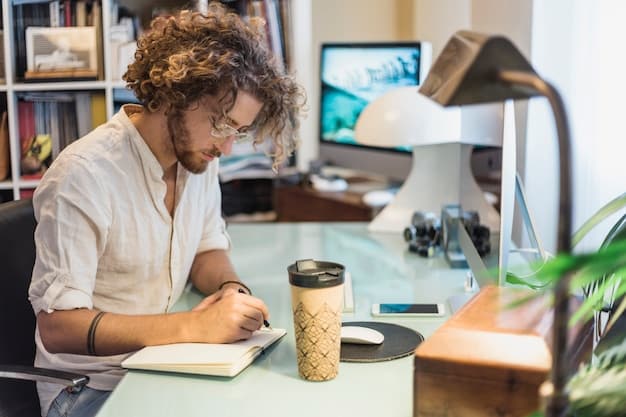 A person writing down potential interview questions on a notepad while sitting at a desk. The room is an office with a bookshelf and a computer in the background.
