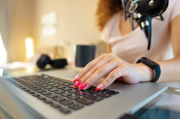 A close-up of a hand typing a personalized email pitch on a laptop, with a microphone and headphones in the background, symbolizing focused effort in crafting podcast guesting requests.