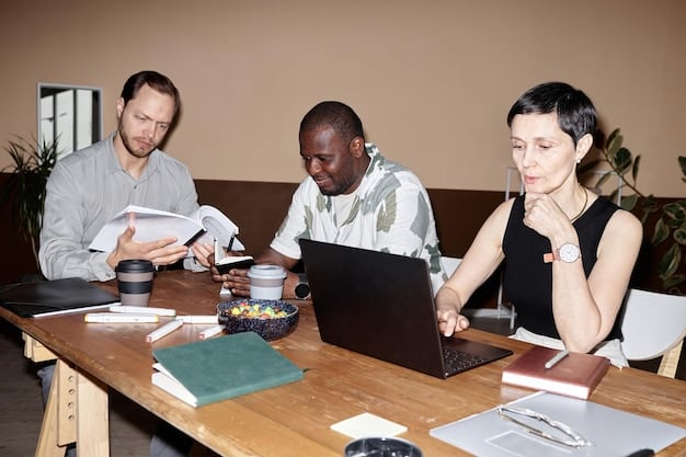 A diverse group of people collaborating around a table, looking at laptops and documents, symbolizing a team effort in preparing and promoting media content. There are coffee cups and bright natural light.