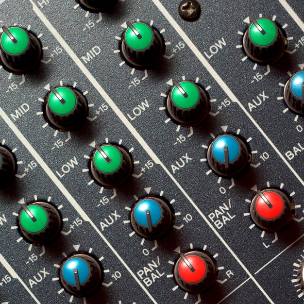 A close-up of a sound mixing board with sliders and knobs, indicating audio level adjustments.