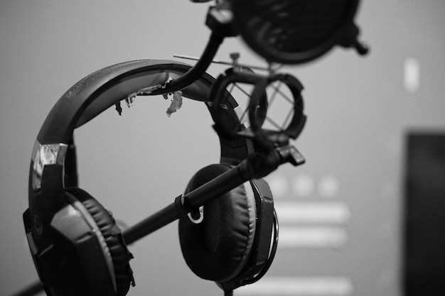 A pair of professional, circumaural monitoring headphones resting on a microphone stand, with a blurred studio background.