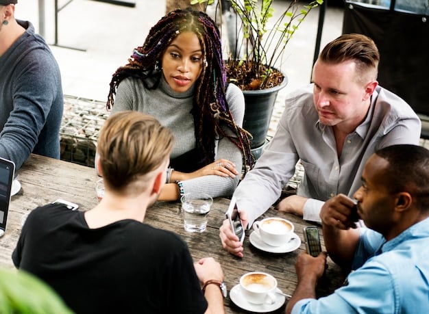 A diverse group of people at a networking event, engaging in conversations, with one person handing a business card to another. The background shows a lively, professional atmosphere conducive to making connections.